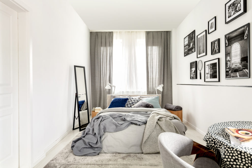 Image of a small bedroom with floor-to-ceiling windows behind the bed. Tips for how to clean your rental home before leaving. Shark clean UK vacuums